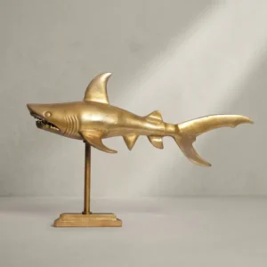 Dreiviertelansicht der Design-Dekofigur Hai aus mattgoldenem Aluminium, die die detaillierte Ausarbeitung der Flossen und des Kopfes hervorhebt._#sku_SAFWL7.169#