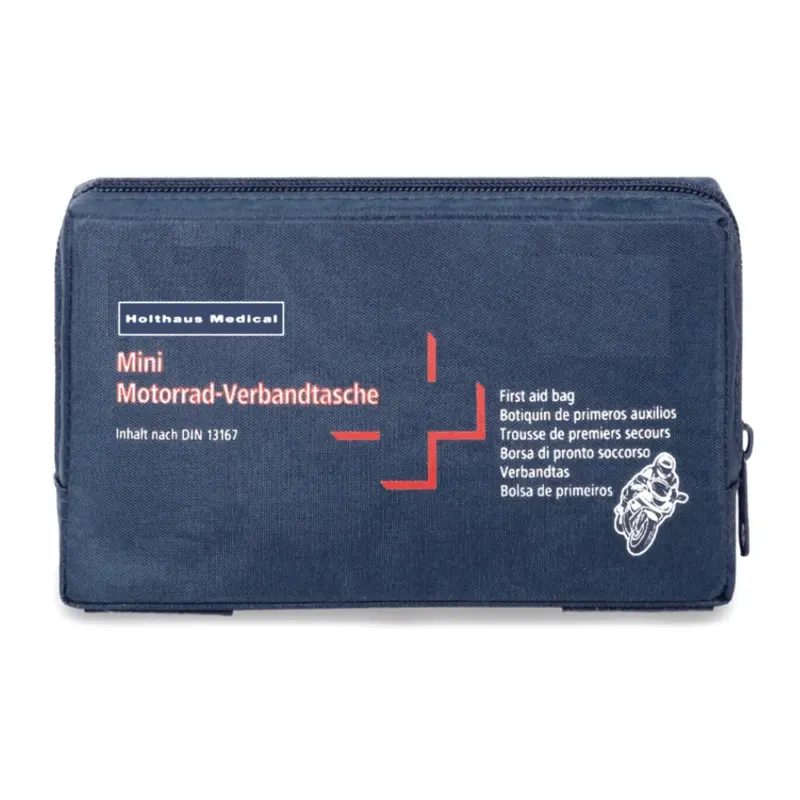 Eine dunkelblaue Erste-Hilfe-Tasche mit dem Aufdruck „Holthaus Mini Motorrad Verbandtasche DIN 13 16“ in weißer und roter Schrift. Die Tasche zeigt außerdem eine kleine Motorradabbildung und enthält mehrsprachige Etiketten, die darauf hinweisen, dass es sich um eine Erste-Hilfe-Ausrüstung nach DIN 13167 handelt, hergestellt von Holthaus Medical GmbH & Co. KG.
